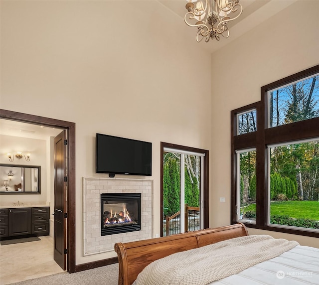 bedroom with light carpet, a towering ceiling, connected bathroom, and a fireplace