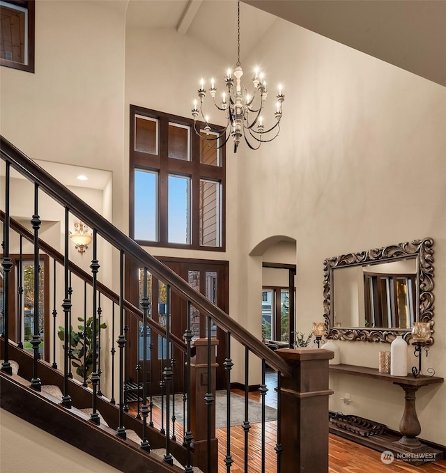 stairs with high vaulted ceiling, a wealth of natural light, hardwood / wood-style floors, and beamed ceiling