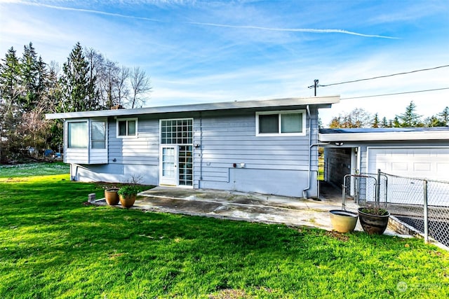 back of house with a garage and a lawn