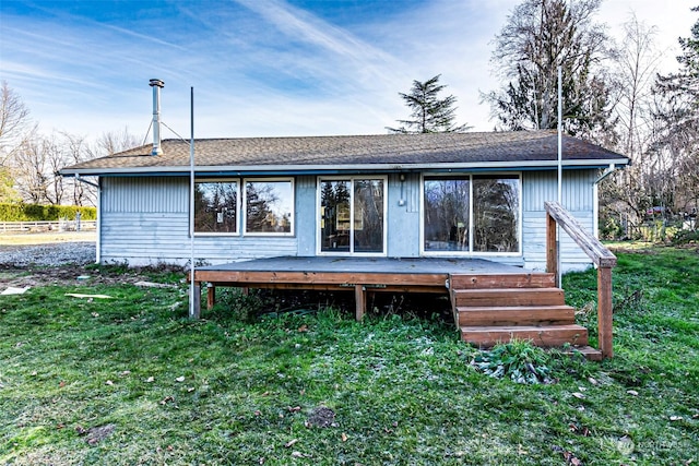 back of property featuring a deck and a lawn