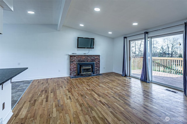 unfurnished living room featuring a brick fireplace, hardwood / wood-style floors, and lofted ceiling with beams