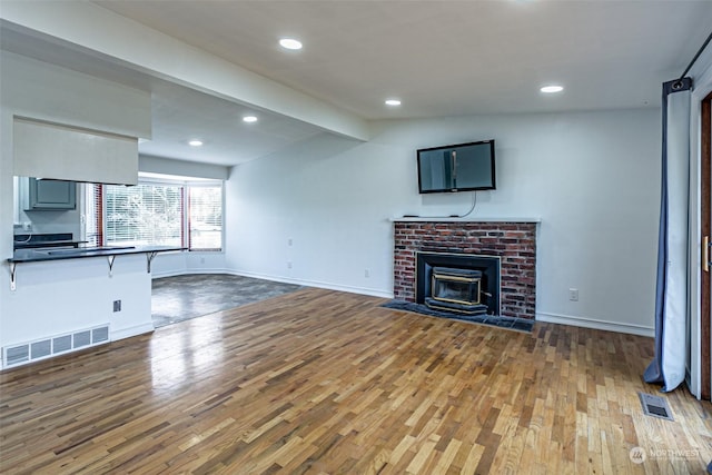 unfurnished living room with light hardwood / wood-style floors, vaulted ceiling with beams, and a brick fireplace