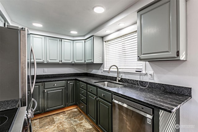 kitchen with sink, stainless steel appliances, dark stone countertops, and gray cabinetry