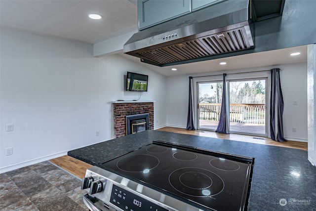 kitchen with ventilation hood, a fireplace, and electric stove