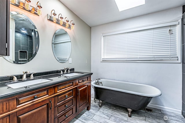 bathroom featuring a bath, a skylight, and vanity