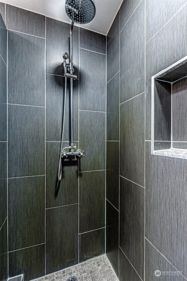 bathroom with a textured ceiling and tiled shower