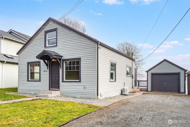 bungalow-style house featuring entry steps, an outdoor structure, a detached garage, driveway, and a front lawn