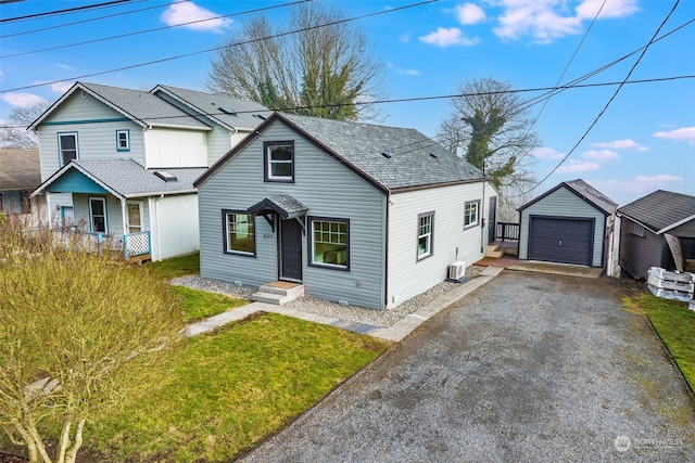 view of front of home featuring driveway, a garage, roof with shingles, an outbuilding, and a front yard