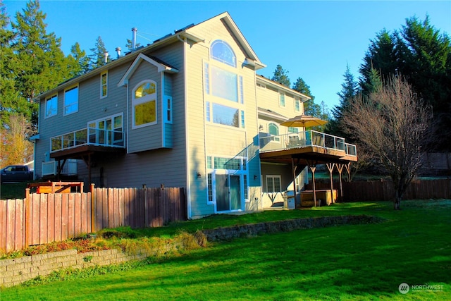 rear view of house featuring a wooden deck and a lawn