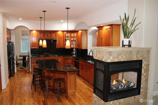 kitchen featuring a center island, backsplash, light wood-type flooring, and decorative light fixtures