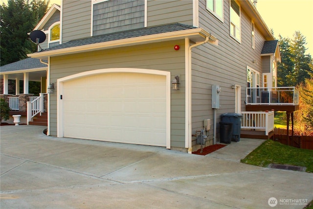 property exterior at dusk featuring a garage, concrete driveway, and a shingled roof