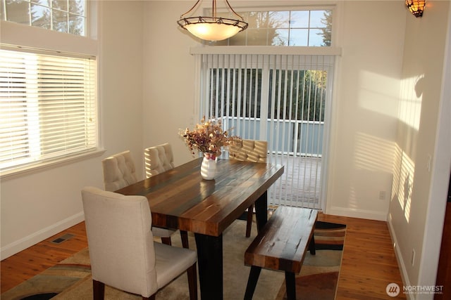 dining area featuring wood finished floors, visible vents, and baseboards