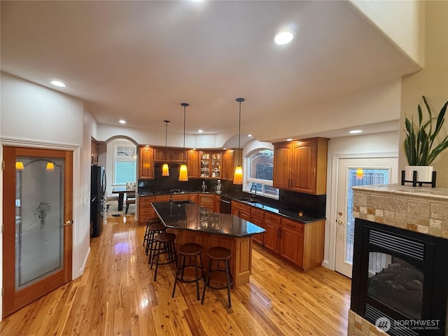 kitchen with tasteful backsplash, light wood-style floors, a breakfast bar area, brown cabinets, and black appliances