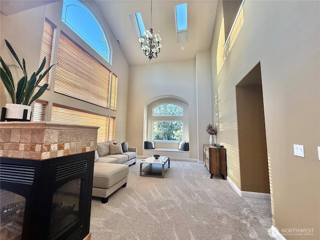 sitting room with carpet floors, high vaulted ceiling, a brick fireplace, a chandelier, and baseboards