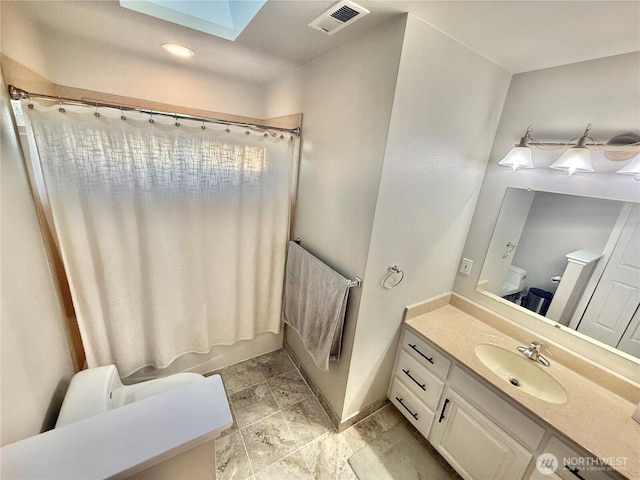 full bathroom featuring a skylight, visible vents, toilet, shower / tub combo, and vanity