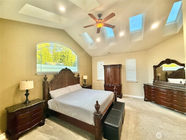 bedroom featuring lofted ceiling with skylight, light colored carpet, baseboards, and a ceiling fan