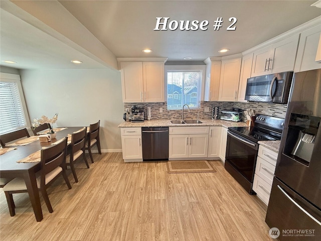 kitchen featuring stainless steel appliances, a sink, white cabinetry, light wood-type flooring, and decorative backsplash