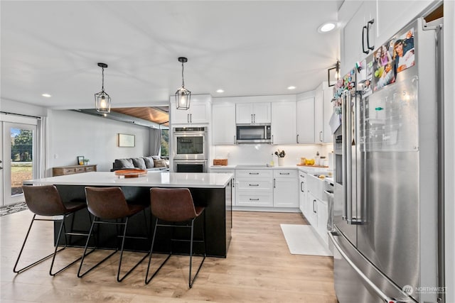 kitchen featuring white cabinets, pendant lighting, a breakfast bar, and stainless steel appliances