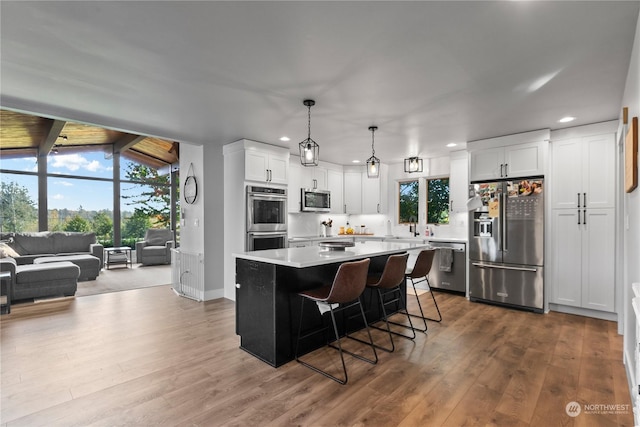 kitchen featuring white cabinets, a kitchen island, vaulted ceiling with beams, pendant lighting, and stainless steel appliances