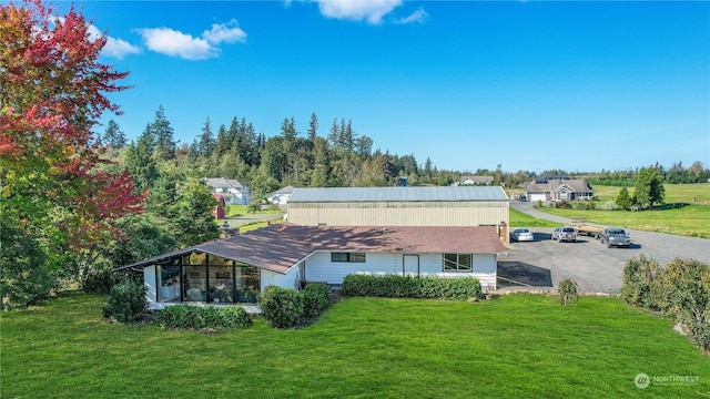 back of property with a lawn and a sunroom