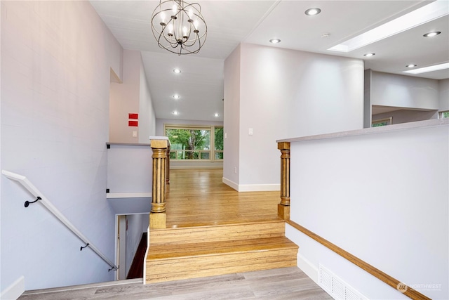 staircase featuring hardwood / wood-style flooring and a chandelier