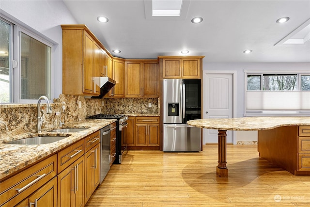 kitchen featuring stainless steel appliances, decorative backsplash, sink, light hardwood / wood-style floors, and light stone counters