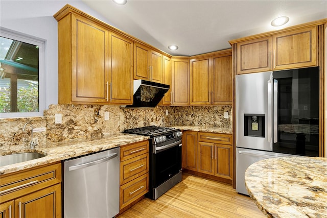 kitchen with stainless steel appliances, decorative backsplash, sink, light hardwood / wood-style floors, and light stone counters