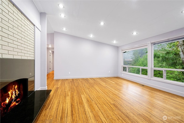 unfurnished living room featuring light wood-type flooring and a fireplace