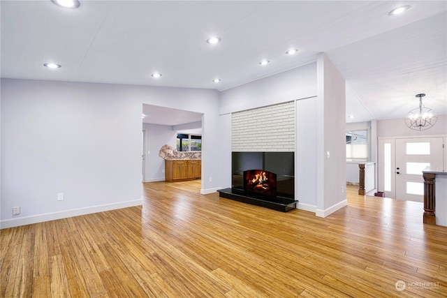 unfurnished living room with light hardwood / wood-style flooring, lofted ceiling, and a chandelier