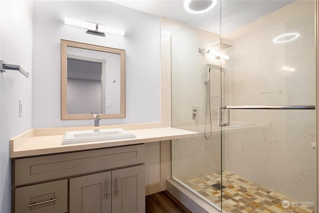 bathroom featuring wood-type flooring, walk in shower, and vanity