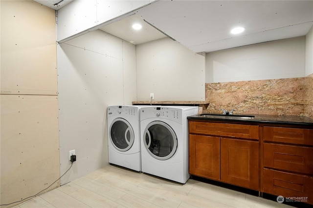 laundry room with sink, washing machine and dryer, and cabinets