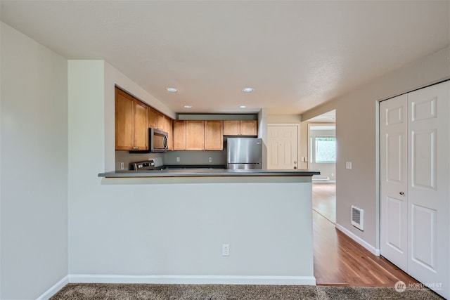 kitchen featuring kitchen peninsula, light colored carpet, and stainless steel appliances