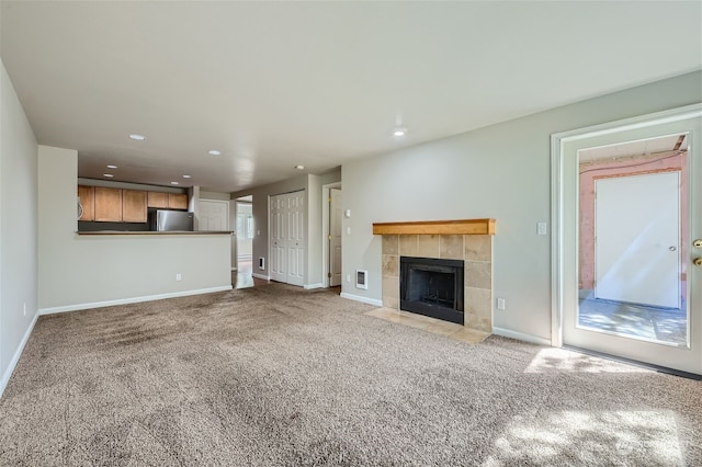 unfurnished living room with a tile fireplace and light carpet