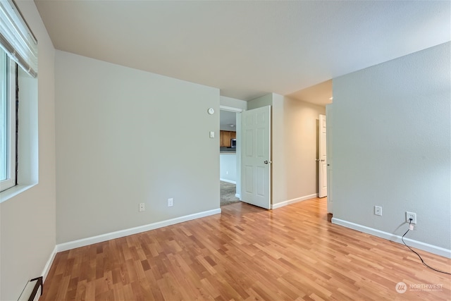 empty room featuring a baseboard radiator and light wood-type flooring