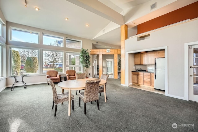 dining area with dark carpet, beam ceiling, and high vaulted ceiling