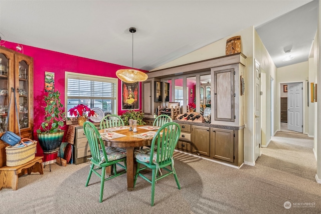 carpeted dining room featuring vaulted ceiling