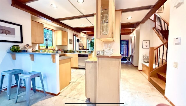 kitchen with stainless steel dishwasher, beamed ceiling, kitchen peninsula, light tile patterned floors, and a breakfast bar area