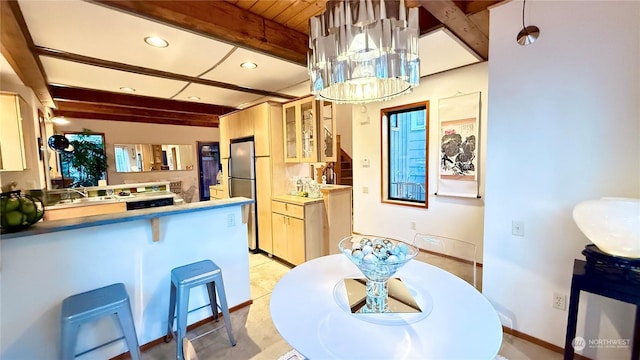 kitchen with kitchen peninsula, pendant lighting, a breakfast bar, beamed ceiling, and stainless steel refrigerator