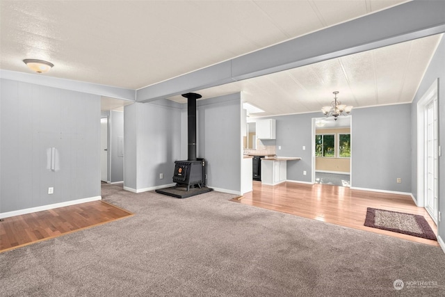 unfurnished living room featuring crown molding, carpet, a wood stove, and an inviting chandelier