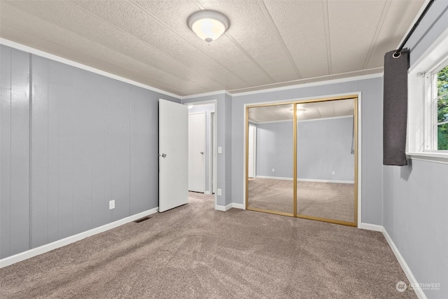 unfurnished bedroom with crown molding, carpet floors, and a closet