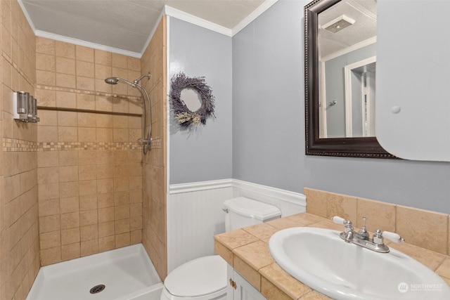 bathroom featuring crown molding, vanity, toilet, and a tile shower