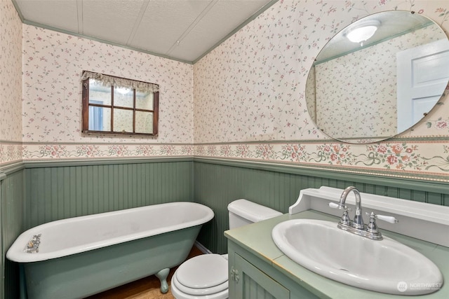 bathroom with toilet, a textured ceiling, ornamental molding, vanity, and a bathing tub