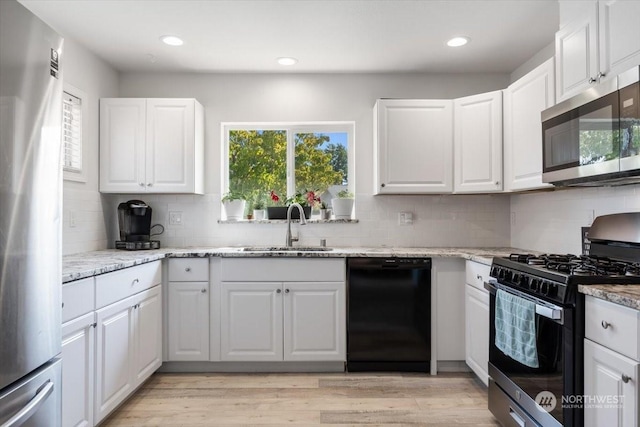 kitchen featuring white cabinetry, sink, tasteful backsplash, and black appliances