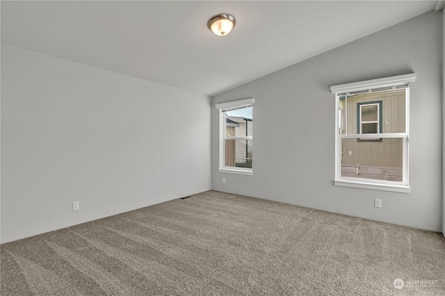 carpeted empty room featuring vaulted ceiling