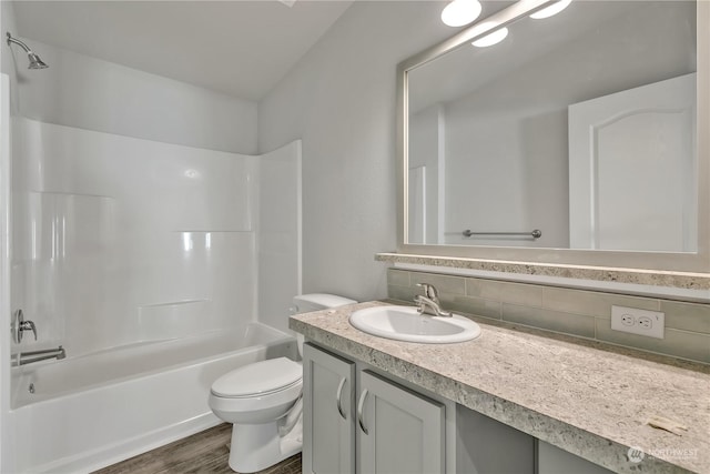 full bathroom featuring wood-type flooring, backsplash, bathing tub / shower combination, toilet, and vanity