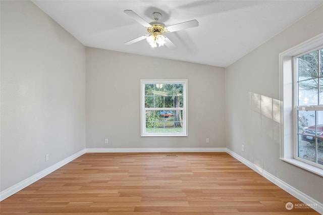 unfurnished room featuring a wealth of natural light, light hardwood / wood-style floors, ceiling fan, and vaulted ceiling