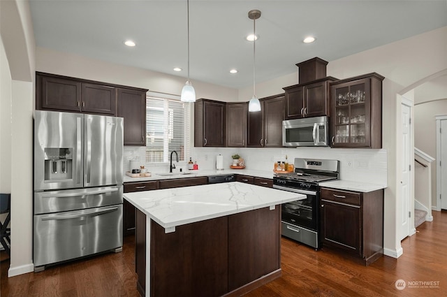 kitchen with hanging light fixtures, sink, dark wood-type flooring, a kitchen island, and stainless steel appliances