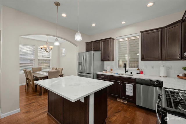 kitchen with pendant lighting, stainless steel appliances, sink, dark hardwood / wood-style floors, and dark brown cabinets