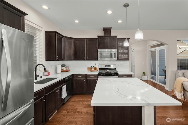 kitchen featuring a center island, stainless steel appliances, tasteful backsplash, sink, and hanging light fixtures