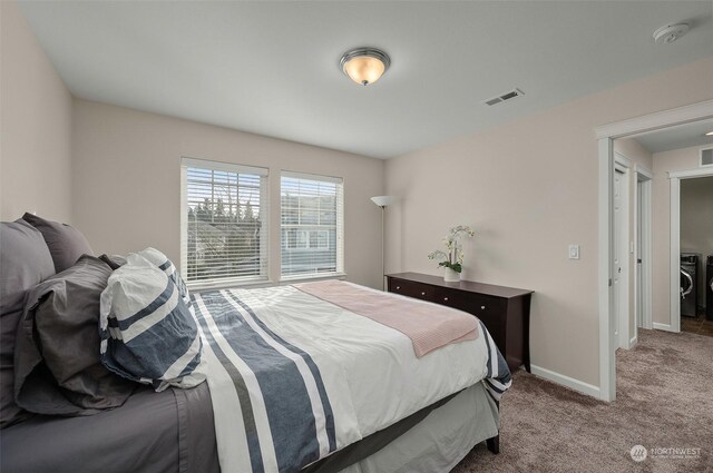 bedroom with light colored carpet and washing machine and dryer